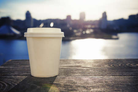 paper cup with take-out coffee on city backgroundの写真素材