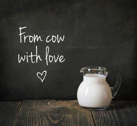 glass jug of milk on blackboard with textの写真素材