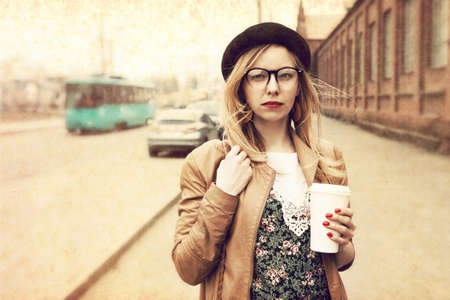Stylish woman in the street drinking morning coffee. Vintage paper texturedの写真素材