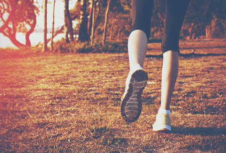 Girl jogging outside. Feet running on grassの写真素材