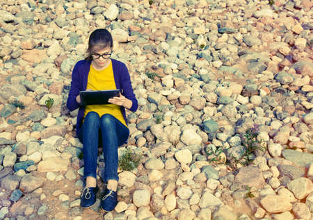 pretty girl using digital tablet at stone coastの写真素材