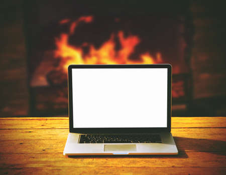 laptop with blank screen for copyspace on wooden table on fireplace backgroundの写真素材
