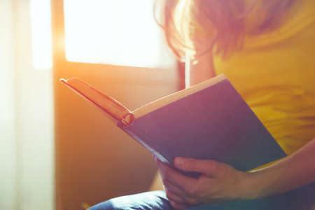 hands holding book and reading in sunlightの写真素材