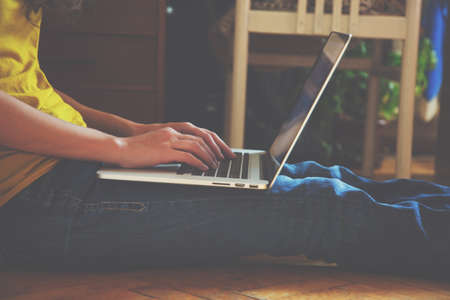 Hands using laptop and typing on wooden floor at homeの写真素材