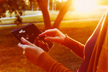hands holding digital tablet pc in summer sunset light