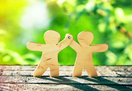 Wooden little men holding hands on natural green background. Symbol of friendship, ecology and teamworkの写真素材