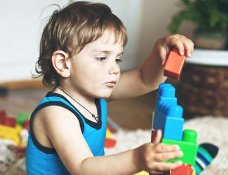 cute boy playing with toy blocks and bricks