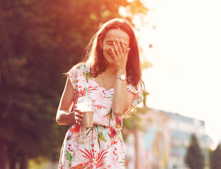 pretty girl with milk shake laughing at the streetの写真素材