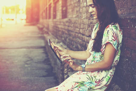 girl holding digital tablet pc at street in sunrise lightの写真素材