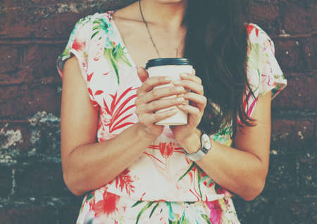 hands holding morning coffee cup on brick wall backgroundの写真素材