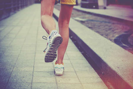 Girl jogging in park. Feet running on roadの写真素材