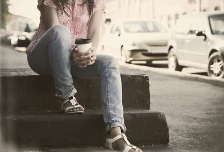 hands holding morning coffee cup at city street