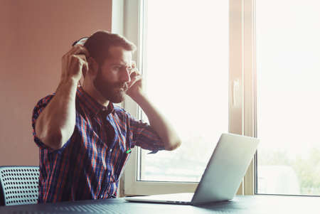 handsome bearded man  in headphones listening to music with laptopの写真素材