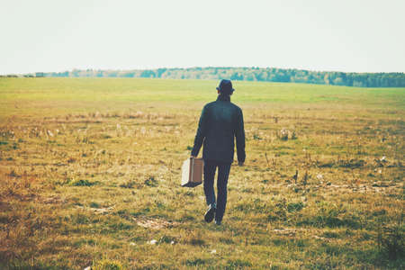 man going with suitcase in field. Concept freedom, loneliness or traveling conceptの写真素材