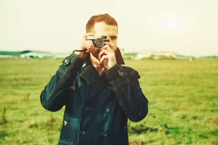 Bearded man holding retro camera and taking photoの写真素材