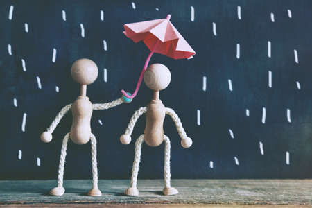 wooden little men as couple under umbrella in rainの写真素材