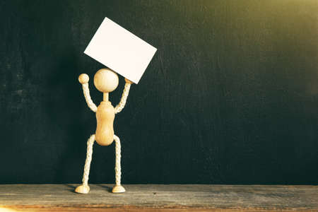 Wooden little man holding blank paper card.の写真素材