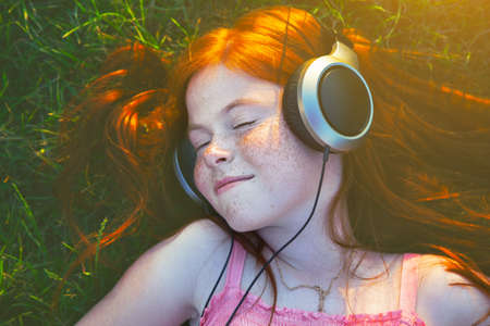 redhead girl with headphones listening to music dreaming