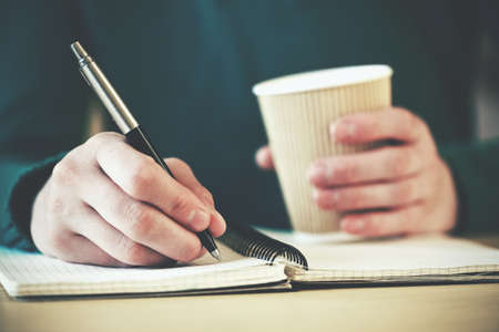 hands with pen writing on notebook with morning coffeeの写真素材