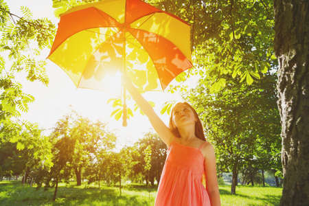 Happy redhead girl with umbrella in summer sun. Freedom, summer, childhood conceptの写真素材