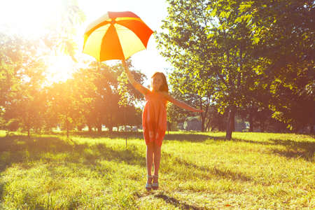 Happy redhead girl with umbrella in summer sun. Freedom, summer, childhood conceptの写真素材