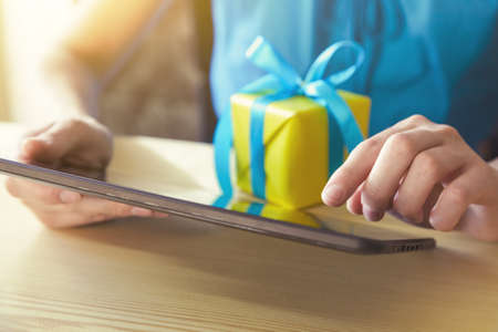 hands with gift box and digital tabletの写真素材