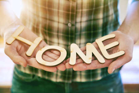 Hands holding wooden letters with word Home. Sweet home or house conceptの写真素材