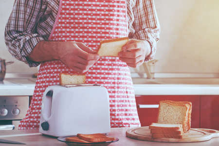 man making toasts with toaster for morning breakfastの写真素材