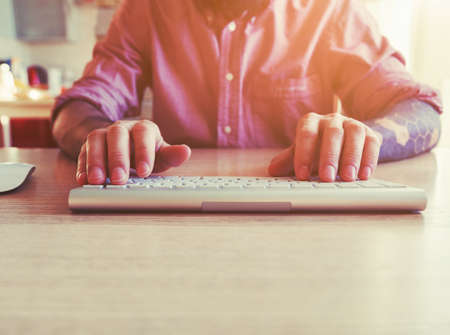 male hands working with computer with wireless keyboard and mouseの写真素材