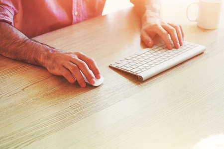 male hands working with computer with wireless keyboard and mouseの写真素材
