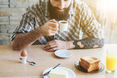 bearded man with breakfast and cup of morning coffeeの写真素材