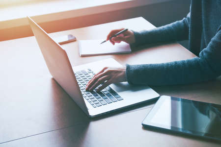 hand with laptop and notebook at workplaceの写真素材