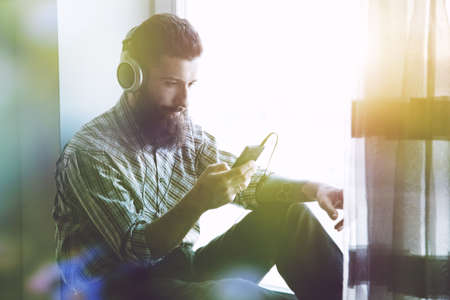 bearded man in headphones listening to music with smartphone appの写真素材