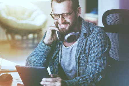 smiling man with digital tablet and headphonesの写真素材
