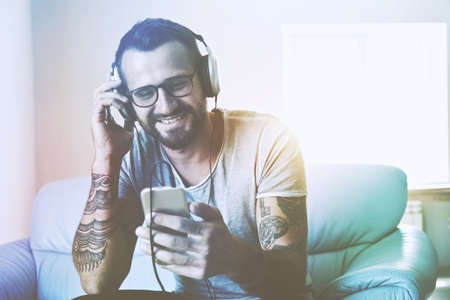 smiling man listening to music with headphones and smart phone