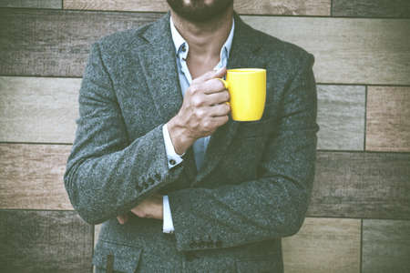 businessman hand holding morning coffee at wall background