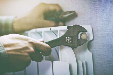 service man hands with wrench near radiatorの写真素材
