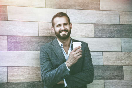 portrait of handsome businessman having break holding morning paper cup of coffeeの写真素材