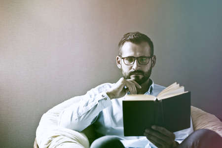 Handsome man reading interesting book. Copy space for textの写真素材