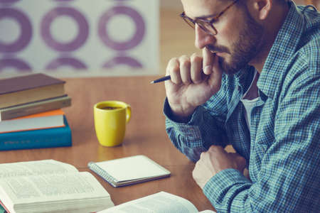 man reading book with cup of coffee at home