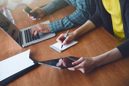 man and woman working together with laptop and writing with penの写真素材