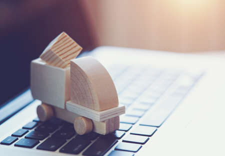 Wooden toy truck on laptop keyboard. Internet shopping, on-line purchase, e-commerce and packages delivery concept.の写真素材
