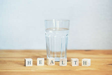 Glass of pure water with health word written in wooden blocksの写真素材