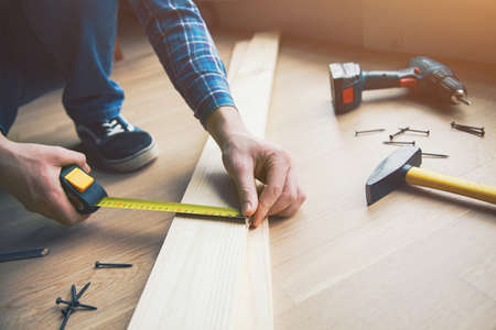 mans hands working with wood measuring tape