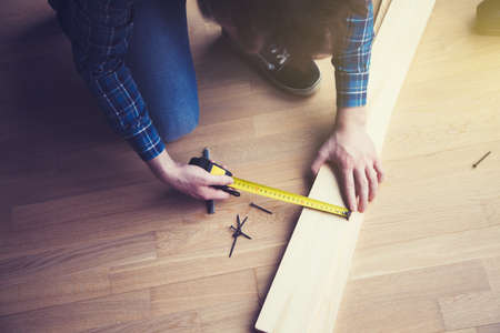 mans hands working with wood measuring tapeの写真素材