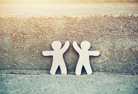 Wooden little men holding hands. Symbol of friendship, love and teamwork