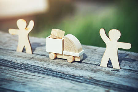 Wooden model of cargo truck delivering box from one man to another. Shipping and transportation...