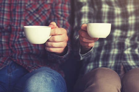 couple with two cups of morning coffee in plaid shirtsの写真素材