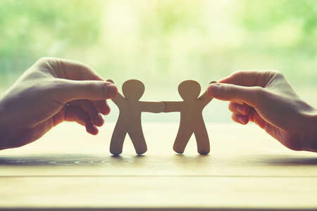 couple holding in hands wooden toy men as symbol of love and friendship