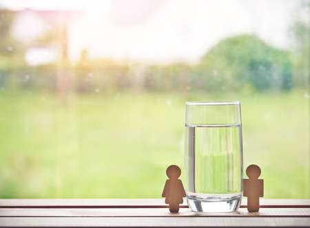 glass of water with wooden woman and man. Space for textの写真素材